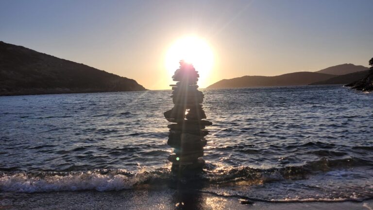 A tower of stones on the beach at sunset